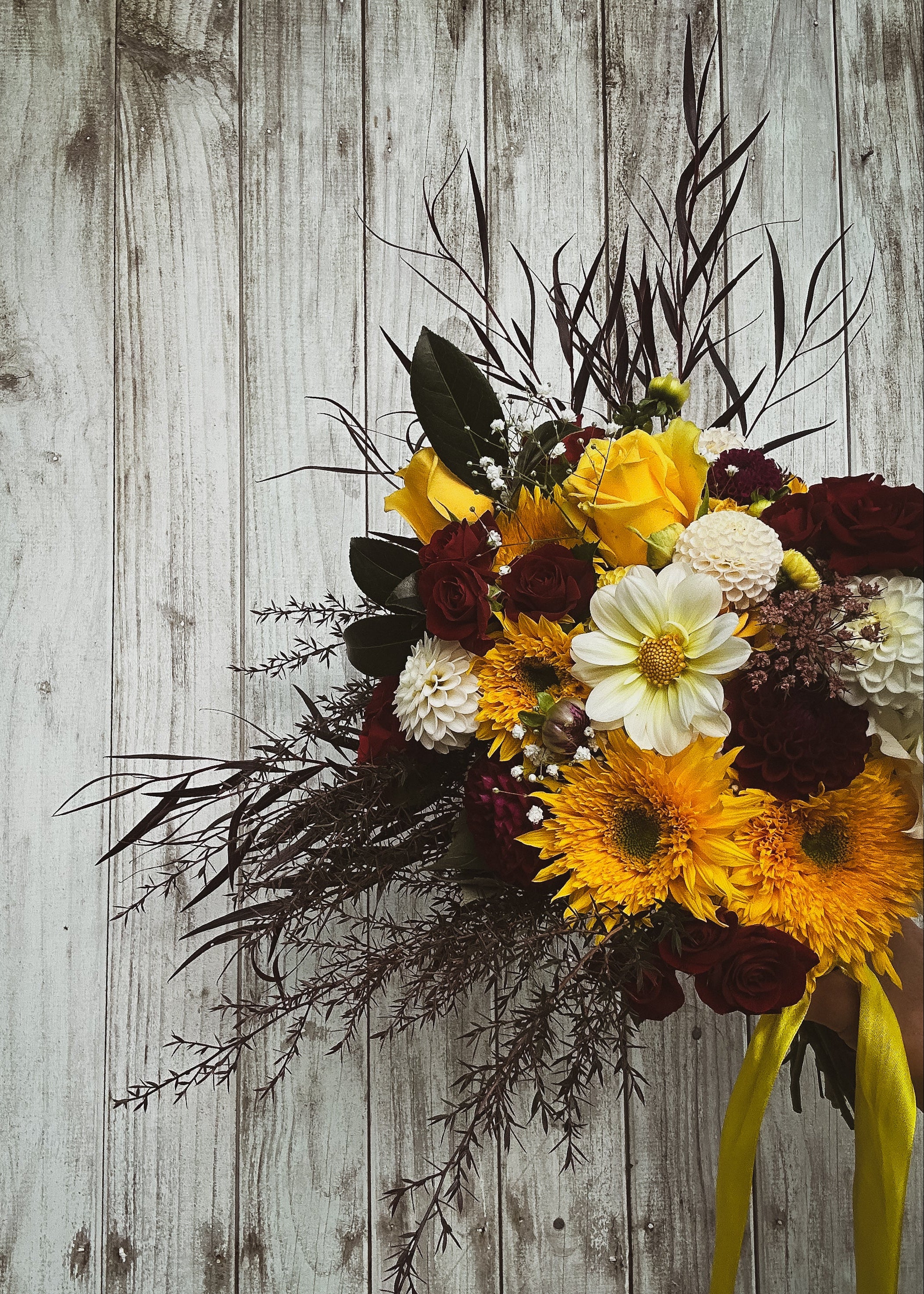 Wildstyler wedding bouquet with bright sunflowers and deep red roses. Wild textures for a statement bridal bouquet. Koputaroa, NZ